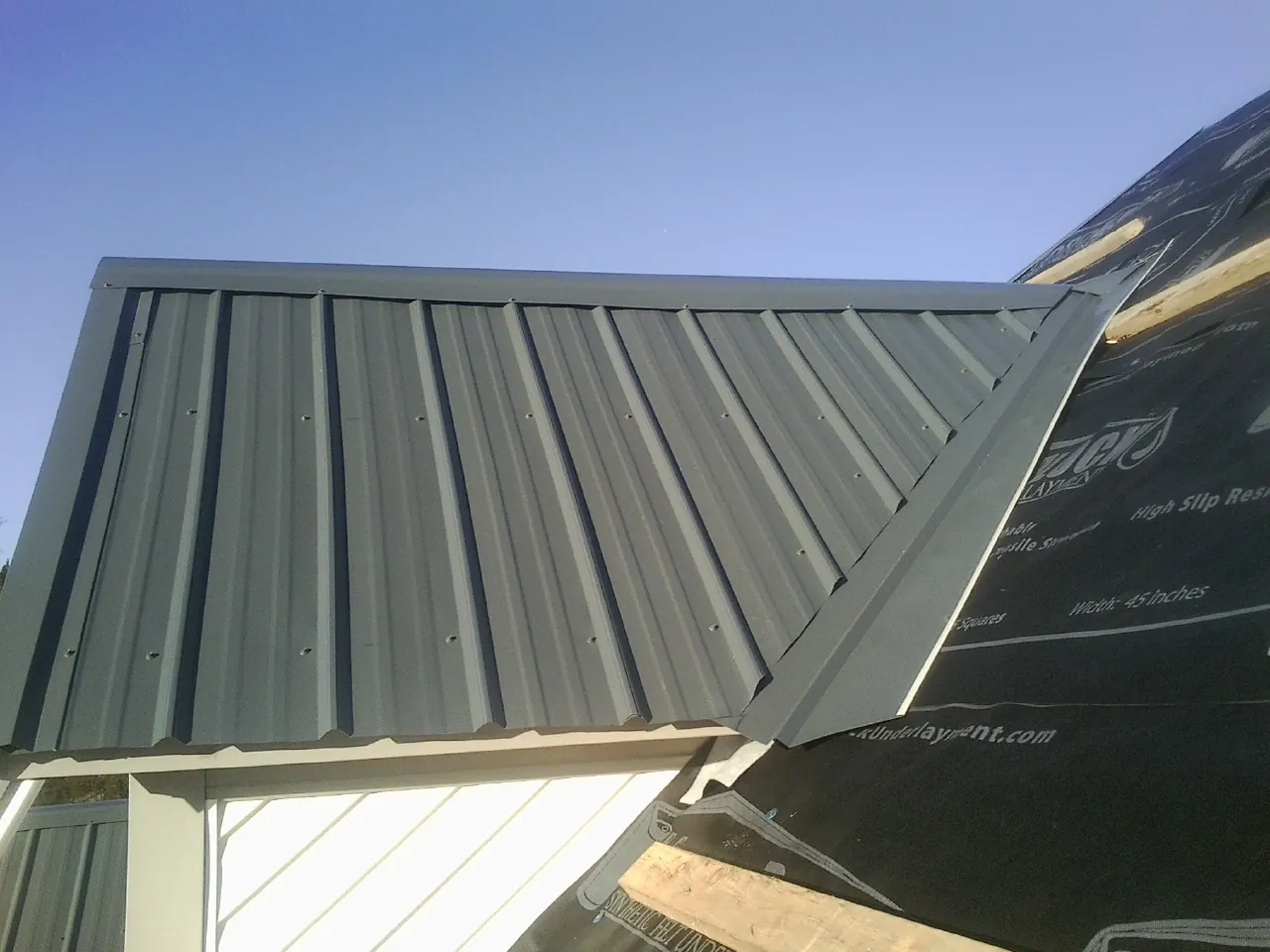 Gray metal roof panels going on over a garage gable in Yellow Pine