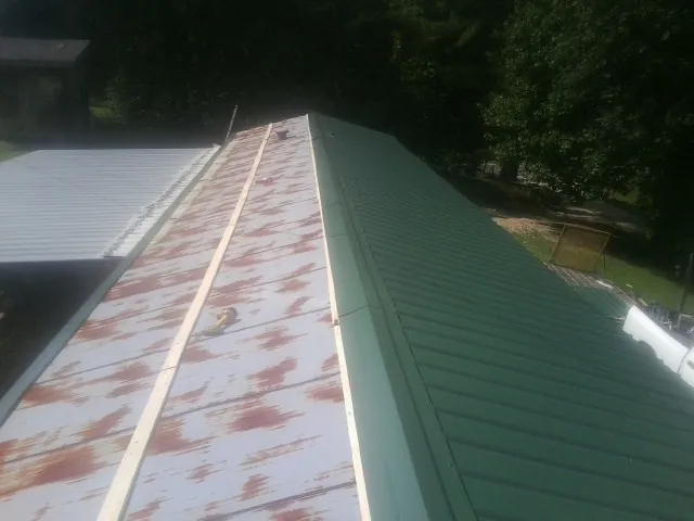 Old rusted panels beside newly installed green metal roofing — Wind Damage Roof Repair by Roofing Brothers in Yellow Pine