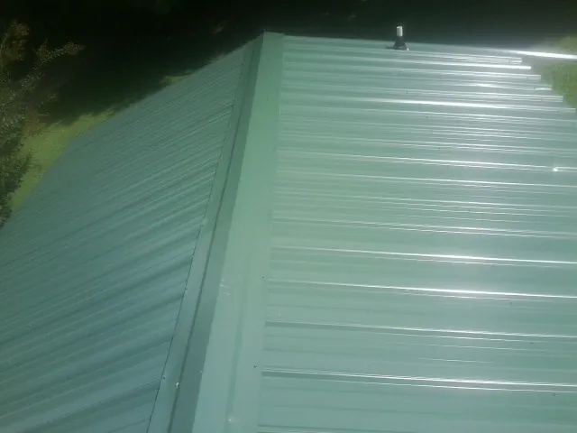 New green metal panels meeting at the ridge of a roof — Flat Roof Repair work by our crew in Yellow Pine