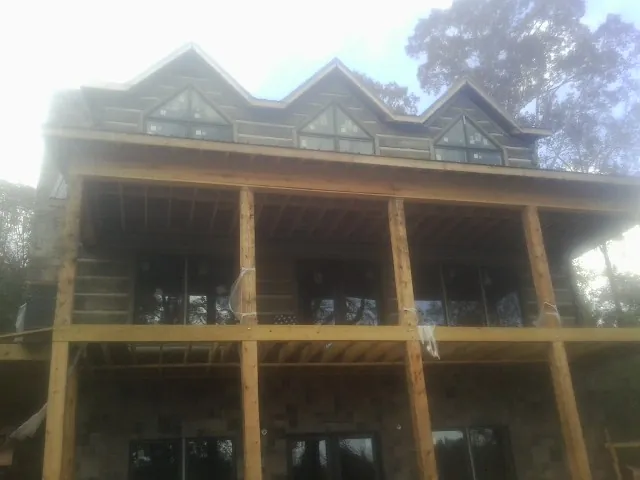Dormers and porch framing on a large log home under construction — Roof Coating work by our crew in Yellow Pine
