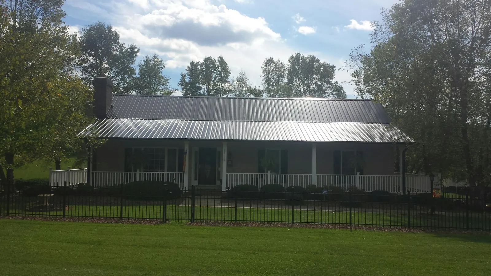 Gray metal roof on a brick ranch with a full width front porch — Gutter Guard Installation work by our crew in Yellow Pine